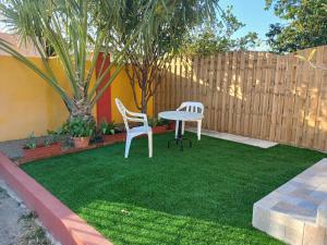 two chairs and a table in a backyard with a fence at Sunny Isle Apartment in Rooi Master
