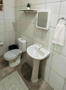 a white bathroom with a toilet and a sink at Pousada Caribe Amazônico Alter do Chão - 1 quarteirão da Orla de Alter in Alter do Chao