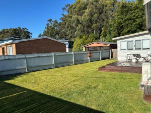 a backyard with a fence and a grass yard at The Boat House in Strahan +34 photos