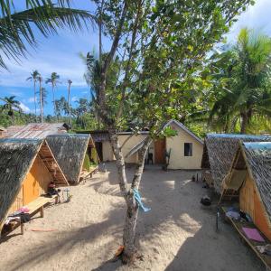a group of huts and a tree in the sand at Island Crib in El Nido