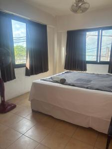 a bedroom with a bed with blue sheets and two windows at Coffeeisland in Nathon