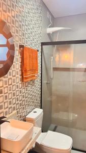 a bathroom with a toilet and an orange towel at Pousada Studio Siriú in Garopaba