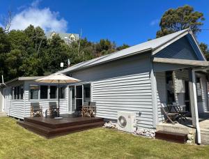 a small house with a deck and an umbrella at The Boat House in Strahan