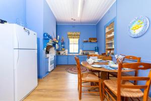 a blue kitchen with a table and a white refrigerator at Winery Cottage in Tanunda