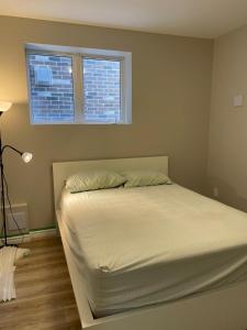 ein Bett in einem Schlafzimmer mit Fenster in der Unterkunft New Basement Apartment unit sleeps 4 in Oakville