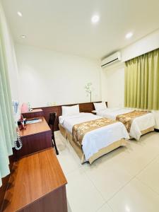 a hotel room with two beds and a desk at Frank B&B in Jincheng
