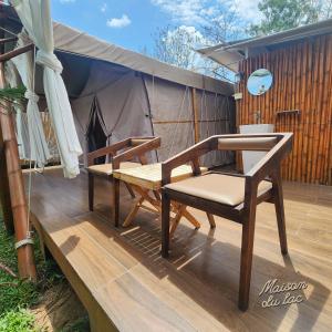 a deck with two chairs and a table and a tent at Maison Du Lac The Safari Tent in Wang Nam Khieo