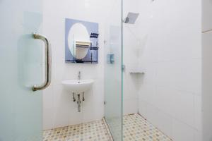 a bathroom with a sink and a glass shower at Urbanview Hotel Executive Residence Semarang by RedDoorz in Candi