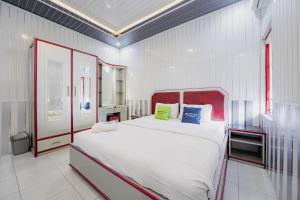 a bedroom with a large white bed in a room at Urbanview Hotel Executive Residence Semarang by RedDoorz in Candi