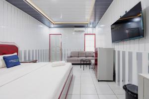 a room with a bed and a couch and a tv at Urbanview Hotel Executive Residence Semarang by RedDoorz in Candi