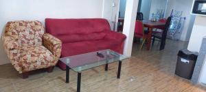 a living room with a red couch and a glass table at Lotus Appartementen Nickerie in Majoor Fernandes