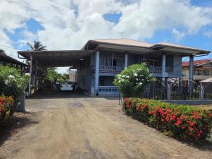 a white house with a gate and flowers at Lotus Appartementen Nickerie in Majoor Fernandes
