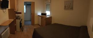 a small room with a bed and a desk with a television at Be Myhôtel in Évreux