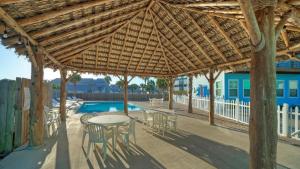 a patio with a table and chairs under a wooden umbrella at Ocean Devotion by AvantStay in Port Aransas