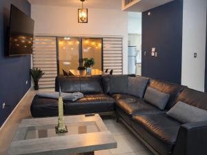 a brown leather couch in a living room with a table at Casa Morada in Ciudad Juárez