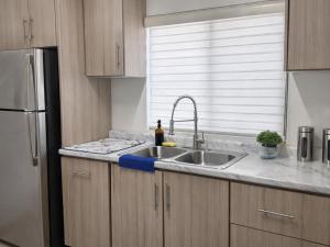 a kitchen with a sink and a stainless steel refrigerator at Casa Morada in Ciudad Juárez