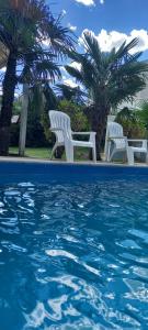 two white chairs sitting next to a swimming pool at Casa con pileta San Luis Juana Koslay in Juana Koslay 