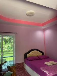 a bedroom with a bed with purple sheets and a window at Martin, Local Guide & Camping in Ban Phang Kan Nua