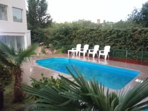 a group of white chairs sitting next to a swimming pool at Casa con pileta San Luis Juana Koslay in Juana Koslay  +1 photo