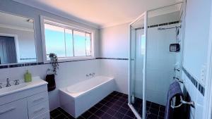 a bathroom with a tub and a sink and a shower at Diamond Beach Getaway - Diamond Beach in Diamond Beach +14 photos