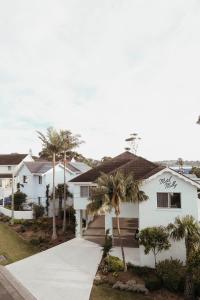 a white house with palm trees and a driveway at Motel Molly - Boutique Hotel Mollymook in Mollymook