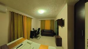 a room with a bed and a couch and a chair at Kings Rest Bed And Breakfast in Gaborone