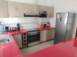 a kitchen with red counter tops and a refrigerator at CASA PREMIUM Estadio Carlos Dittborn in Arica