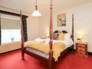 a bedroom with a four poster bed and a window at The Old Post Office in Matlock