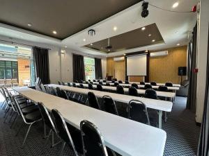 a conference room with white tables and chairs and a screen at Seree Grand Resort in Hat Yai
