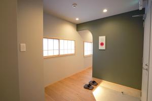a hallway with a green wall and shoes on the floor at ミツカビルヂング in Kofu