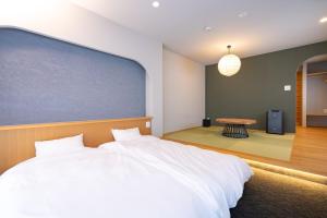 a bedroom with a large white bed and a table at ミツカビルヂング in Kofu