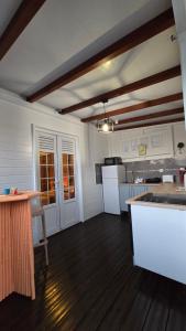 a kitchen with white appliances and a wooden floor at La Cachette in Le Marin