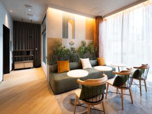 a living room with a couch and tables and chairs at R Hotel Namba East in Osaka