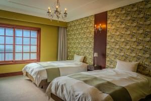 a hotel room with two beds and a window at Ryokan Kiraku in Beppu +33 photos