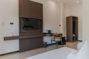a hotel room with a television and a chair at เวลการ์เด้น101 in Ban Hua Phrong