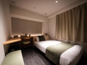a hotel room with two beds and a desk at R Hotel Namba East in Osaka