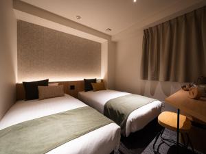 a hotel room with two beds and a window at R Hotel Namba East in Osaka