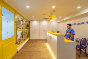 a man standing at a yellow counter in a room at goSTOPS Bengaluru, Indiranagar - Private Rooms & Dorms in Bangalore
