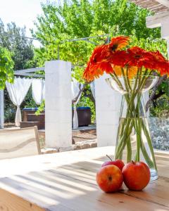 a vase with orange flowers and apples on a table at House With Jacuzzi Among Orchards In Cisternino in Cisternino