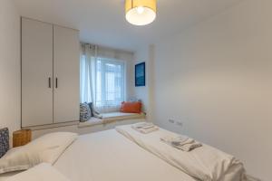 a white bedroom with a bed and a window at Central 2BR - Workspace with Elevator in Varna City