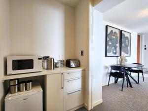 a kitchen with a microwave on a counter with a table at Dreamtime Hahei in Hahei