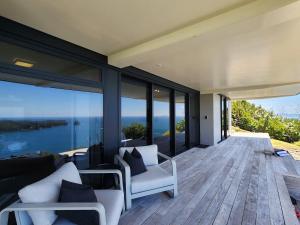 a house with a deck with a view of the ocean at Dreamtime Hahei in Hahei