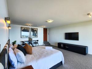 a bedroom with a bed and a flat screen tv at Dreamtime Hahei in Hahei