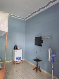 a room with a bed and a tv on a wall at Chambre Bleu - Coco Room Nosy-Be in Nosy Be