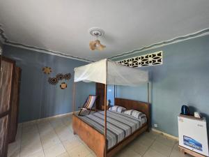 a bedroom with a canopy bed and blue walls at Chambre Bleu - Coco Room Nosy-Be in Nosy Be