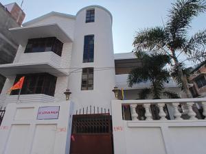 a white house with a gate and a palm tree at Lotus palm in Deoghar