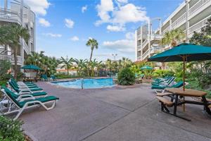 a pool with lounge chairs and a table and an umbrella at Luxury Beach front Condo in Galveston