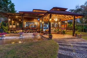 a house with a pavilion with a pond in front at De Bua Valley Resort in Wang Nam Khieo