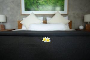 a yellow and white flower on top of a bed at KARMA room in Villa ABSOLUTE Shared Villa in Canggu