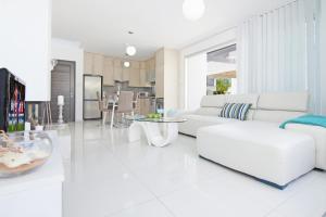 Villa Solebianco Protaras في بروتاراس: غرفة معيشة بيضاء مع أريكة بيضاء وطاولات